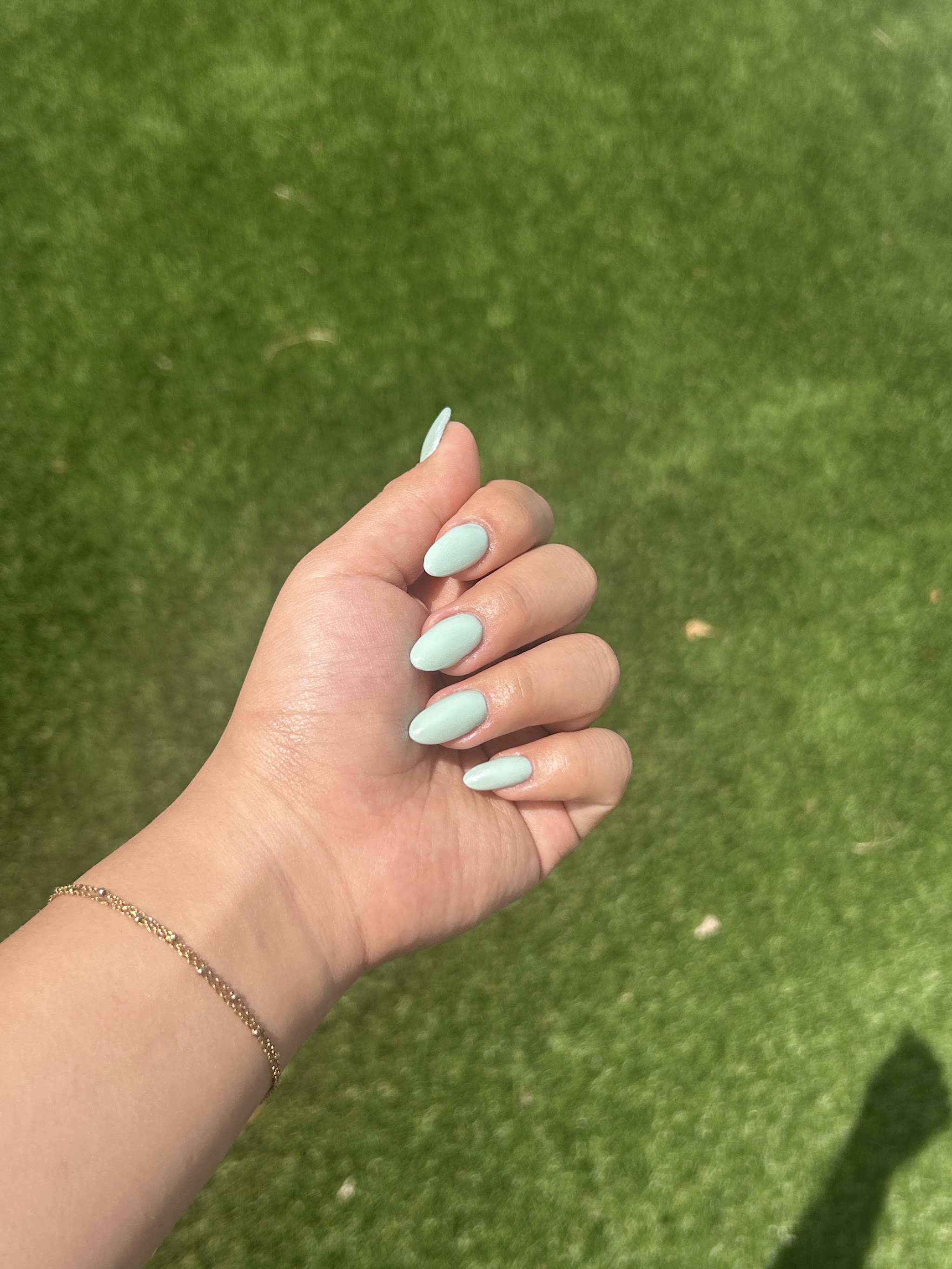 Mintgroene amandelnagels in de zon boven gras