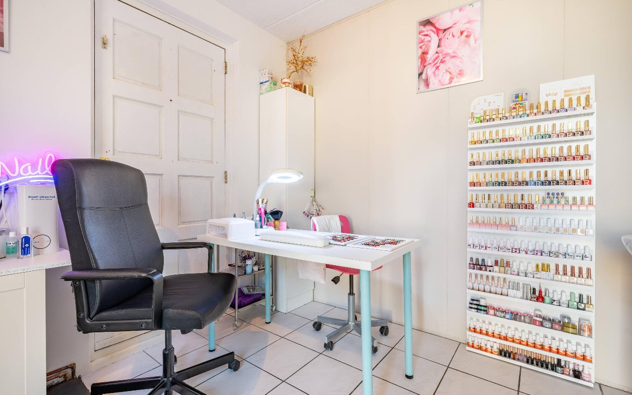 Manicuretafel met lamp voor een wand vol nagellak